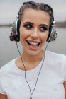 Retrato de uma mulher sorrindo usando fones de ouvido cravados — Fotografia de Stock