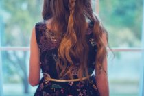 Rückansicht eines Mädchens im Partykleid, das aus dem Fenster schaut — Stockfoto