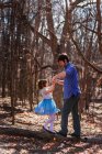 Отец и дочь держатся за руки, стоя на стволе дерева в лесу — стоковое фото