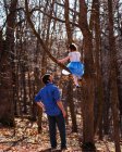 Отец смотрит на дочь, сидящую на дереве — стоковое фото