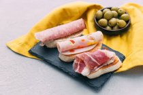 Bruschetta with cured meats and a bowl of olives — Stock Photo