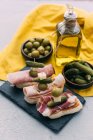 Bruschettas with prosciutto, olives, cheese and gherkins — Stock Photo