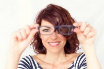 Femme souriante tenant une paire de lunettes — Photo de stock
