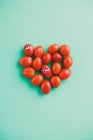 Tomates ciruela con ojos pegajosos en forma de corazón - foto de stock