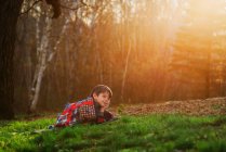 Хлопчик лежить на траві, загорнутий у ковдру на сонці — стокове фото