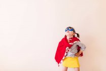 Menina vestida como um super-herói no fundo branco — Fotografia de Stock