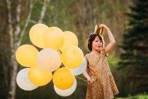 Fille dans une robe en or portant une couronne portant des ballons — Photo de stock
