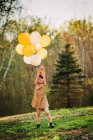 Mädchen im goldenen Kleid mit Krone und Luftballons — Stockfoto