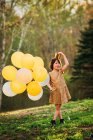Ragazza in abito d'oro con indosso una corona che trasporta palloncini — Foto stock