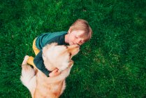 Overhead view of a boy playing with his golden retriever dog — Stock Photo