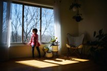 Ragazza seduta alla luce del sole guardando attraverso una finestra — Foto stock