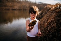Junge am Strand hält Muschel in der Natur — Stockfoto