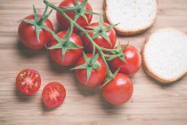 Tomates de vid y tomates cherry con rodajas de pan blanco - foto de stock