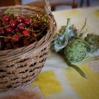 Cesto di vimini con ciliegie e carciofi primo piano — Foto stock