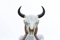 Man holding a bison skull in front of his head — Stock Photo