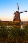 Moinho de vento sobre o canal de água ao pôr do sol, Kinderdijk, Países Baixos — Fotografia de Stock