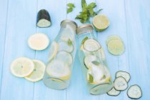 Two water bottles with cucumber, lemon, lime and mint — Stock Photo