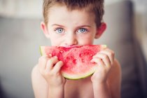 Menino comendo fatia de melancia no fundo claro — Fotografia de Stock