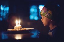 Junge bläst Kerzen auf Geburtstagstorte aus — Stockfoto