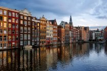 Sonnenuntergang mit den Tanzenden Häusern am Damrak und dem Oudekerksplein Tower, Amsterdam, Niederlande — Stockfoto