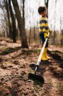Garçon creuser la terre avec une houe — Photo de stock