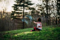 Mädchen sitzt draußen und hält einen Rauchstab in der Hand — Stockfoto