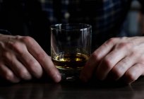 Man sitting at a bar with a glass of whisky — Stock Photo