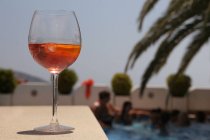 Verre de vin de rose au bord d'une piscine lors d'une fête de piscine — Photo de stock