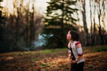Menina soprando uma vara de fumar na natureza — Fotografia de Stock