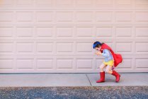 Дівчина біжить через гаражні двері, одягнені як супергерой — стокове фото