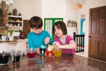 Мальчик и девочка стоят на кухне и умирают пасхальные яйца — стоковое фото