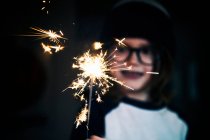 Retrato de um menino sorridente segurando um sparkler — Fotografia de Stock