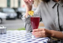 Woman in a cafe drinking a cranberry cocktail — Stock Photo