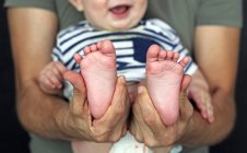 Pai segurando os pés de seu filho — Fotografia de Stock