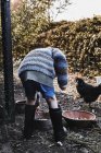 Мальчик кормит курицу в саду — стоковое фото