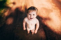 Retrato de un niño sonriente en un pañal parado afuera - foto de stock