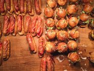 Overhead view of hamburgers and hotdogs on a wooden table — Stock Photo