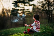 Девушка сидит снаружи с дымящейся палкой — стоковое фото