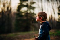 Boy blowing smoking stick in forest — Stock Photo