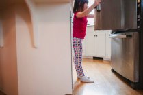 Дівчина дивиться в холодильник — стокове фото