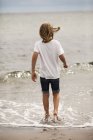 Boy with long hair paddling in the sea — Stock Photo