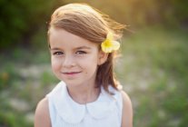 Портрет улыбающейся девушки с цветком в волосах — стоковое фото