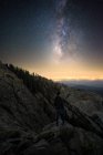 Homem de pé na montanha careca olhando estrelas com Fresno na distância, Califórnia, EUA, América — Fotografia de Stock