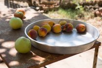 Bandeja metálica de pêssegos e maçãs em uma mesa — Fotografia de Stock