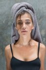 Eine junge Frau mit grauem Kopftuch bereitet sich nach einer Dusche in einer tropischen balinesischen Villa auf ihre Gesichtsmaske vor. — Stockfoto
