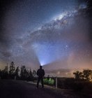 Rückansicht eines Mannes, der auf der Straße steht und in den Nachthimmel blickt — Stockfoto