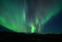 Spectacular auroral display at night over mountain, spectacular auroral and star at night, Iceland — Stock Photo