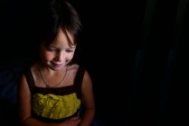 Портрет усміхненої дівчини на темному тлі — стокове фото