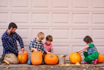 Three kids and a father carving pumpkins — Stock Photo