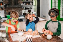 Троє маленьких дітей допомагають готувати на кухні — стокове фото